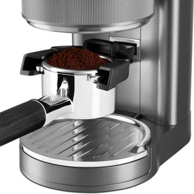 KitchenAid Artisan Coffee Grinder in brushed silver, close-up of portafilter filled with freshly ground coffee beneath the grind chute