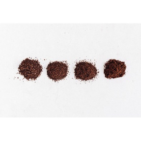 KitchenAid Artisan Coffee Grinder showing four coffee grind size samples ranging from fine to coarse on a white surface