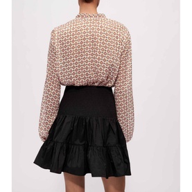 Model wearing Maje Jun Smock Ruffle Mini Skirt in black with elasticated waist, styled with a geometric print blouse