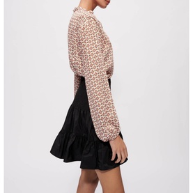Model wearing Maje Jun Smock Ruffle Mini Skirt in black with elasticated waist, styled with a pink floral print blouse