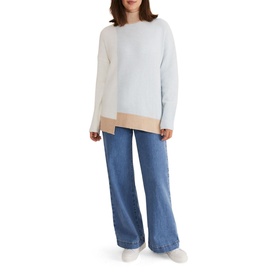 Model wearing Phase Eight Mariella Cosy Asymmetric Sweater in blue colour block with high neck, styled with wide-leg jeans and white trainers