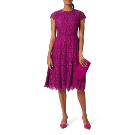 Model wearing Hobbs Rosaleen Dress in purple lace, round neck, capped sleeves, styled with matching clutch and heels