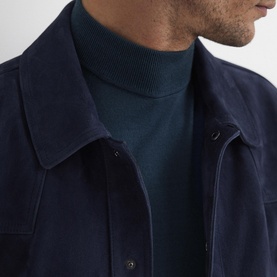 Model wearing Reiss Kelby Turtleneck Sweater in blue wool, styled with a navy suede overshirt. Ribbed turtleneck collar visible