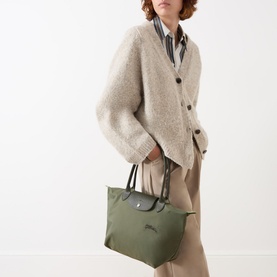 Model carrying Longchamp Le Pliage Green Medium Tote in khaki recycled canvas with silver-tone hardware and leather trim