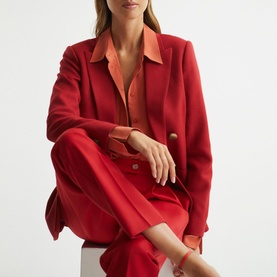 Model wearing Reiss Lola Double Breasted Blazer in red with matching red trousers and orange shirt underneath