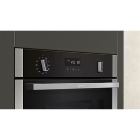 Neff built-in electric oven in black and stainless steel with digital display and rotary control, shown installed in dark grey cabinetry