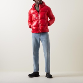 Model wearing Pyrenex Sten Puffer Jacket in red high-shine finish with adjustable hood, styled with light blue jeans and black boots