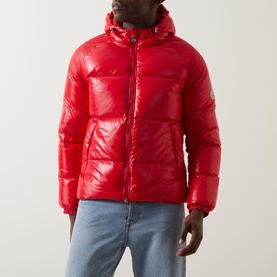 Model wearing Pyrenex Sten Puffer Jacket in red, glossy finish, zip-front, adjustable hood, styled with light blue jeans