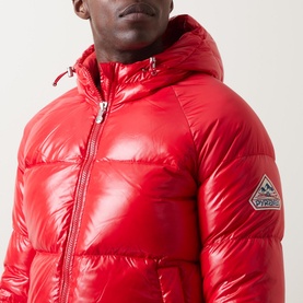 Model wearing Pyrenex Sten Puffer Jacket in red high-shine finish, featuring adjustable hood, zip fastening, and logo patch detail