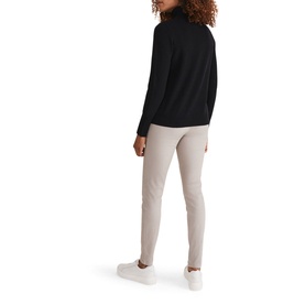 Model wearing Phase Eight Amina Jeggings in brown with exposed side zip, styled with black roll-neck jumper and white trainers
