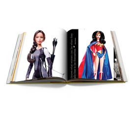 Assouline Mattel: 70 Years of Innovation and Play hardback book open to pages showing Barbie dolls dressed as Katniss and Wonder Woman