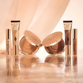 Charlotte Tilbury Beautiful Skin Radiant Concealer set with bronzer compact, displayed in warm golden tones with soft peach background.
