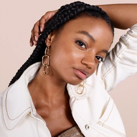 Model wearing Lanc&ocirc;me Teint Idole Ultra Wear Care & Glow foundation, styled with gold chain drop earrings and a white jacket