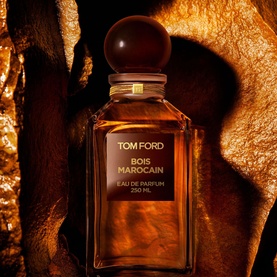 TOM FORD Bois Marocain Eau de Parfum 250ml in amber glass decanter bottle with spherical stopper, set against warm golden stone backdrop