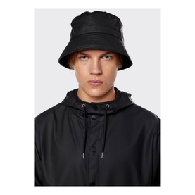 Model with Rains Bucket Hat in black water-resistant fabric, styled with matching black hooded rain jacket
