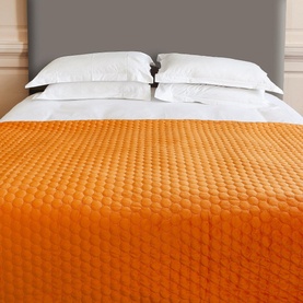 Scatterbox Halo Pumpkin Throw in orange, draped over a double bed with quilted bubble texture, styled with white pillows