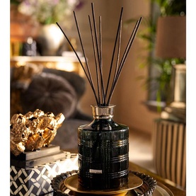 Rituals Round Bottle Petrol reed diffuser in deep blue with black reeds, gold-toned collar, styled on a mirrored tray in a warm home setting