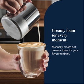 DeLonghi La Specialista Arte milk frother pouring creamy foam into a double-walled glass latte cup