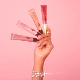 Charlotte Tilbury Pillow Talk Matte Beauty Blush Wand in Pink Pop; hand holding four blush wand tubes fanned out on pink background