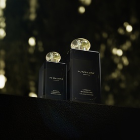 Jo Malone Cypress & Grapevine Cologne Intense in two sizes, black bottles with gold caps on dark reflective surface