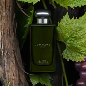 Jo Malone Cypress & Grapevine Cologne Intense bottle in dark green glass with silver cap, styled with vine leaves and grapes