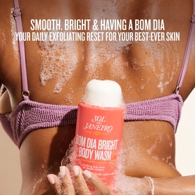 Model with Sol De Janeiro Bom Dia Bright Body Wash, applying foaming formula to back, wearing purple bikini