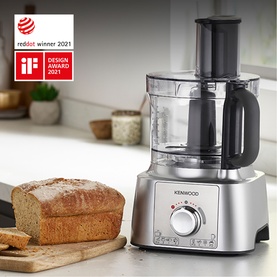 Kenwood Food Processor in silver with large clear bowl, shown on kitchen counter beside sliced brown bread loaf. Red Dot and iF Design Award 2021