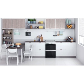 Indesit 60cm white gas freestanding double cooker shown in a modern kitchen setting with dining table and styled cabinetry