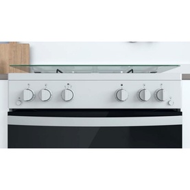 Indesit 60cm white freestanding gas double cooker, showing gas hob with four burners and double oven with black glass door