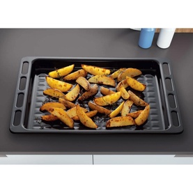 Indesit Gas Freestanding Double Cooker black enamel baking tray filled with roasted potato wedges, shown on a grey surface