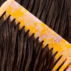 Sol De Janeiro Brazilian Joia Strengthening + Smoothing Shampoo yellow floral comb gliding through dark, smooth hair