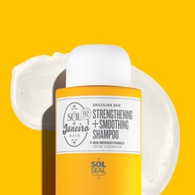 Sol De Janeiro Brazilian Joia Strengthening + Smoothing Shampoo yellow bottle with white lather swatch on yellow background