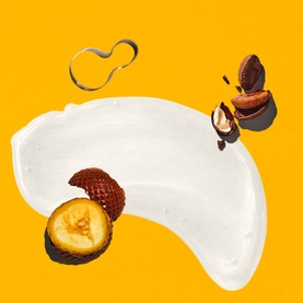 Sol De Janeiro Brazilian Joia Shampoo ingredient shot showing white creamy formula with cupua&ccedil;u nuts on yellow background