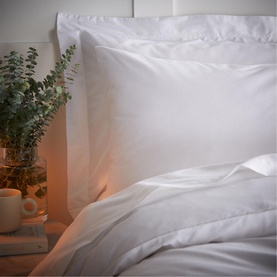 Bianca 200 Thread Count Cooling Tencel Standard Pillowcase Pair in white, styled on a bed with duvet, beside eucalyptus and warm lamp