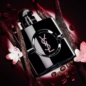 YSL Black Opium Le Parfum black bottle with silver YSL logo, styled with pink florals, vanilla pods and coffee beans backdrop.