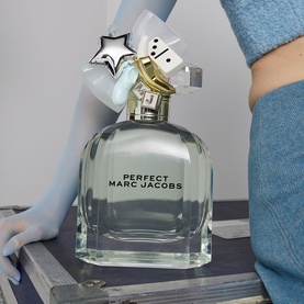 Marc Jacobs Perfect Eau de Toilette 100ml clear glass bottle with star and dice charm topper, held by model in denim