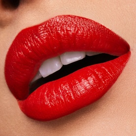 Est&eacute;e Lauder Pure Color Cr&egrave;me Lipstick in Carnal, a bold red shade, shown applied on lips in a close-up beauty shot