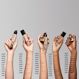 Lanc&ocirc;me Teint Idole Ultra Wear Foundation shown across six hands displaying bottles in a range of shades from light to deep