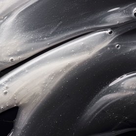 Oribe Hair Alchemy Shampoo close-up texture shot showing silky grey gel formula with water droplets