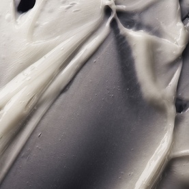Oribe Hair Alchemy Conditioner close-up texture shot showing creamy white and grey formula swirled together