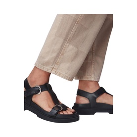 Model wearing Whistles Porto Double Buckle Sandals in black leather, featuring T-bar straps with silver buckles and rubber sole