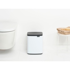 Brabantia Bo Waste Bin 7L in White with dark grey soft-close lid, styled in a bathroom setting beside folded towels
