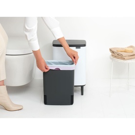Brabantia Bo Waste Bin Hi 12L in White with dark grey base, shown open with liner being placed inside, in a bathroom setting