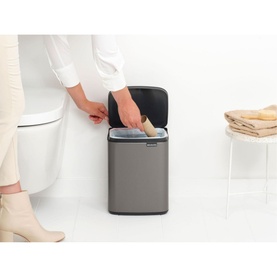 Brabantia Bo Waste Bin 7L in Platinum silver, open lid shown as model places waste inside, bathroom setting