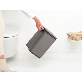 Brabantia Bo Waste Bin 7L in Platinum silver, held by hand in a bathroom setting, showing transport grip and soft-close lid