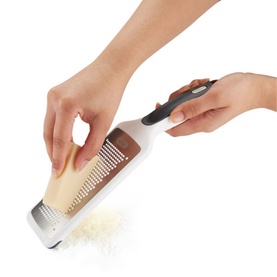 Zyliss Smooth Glide Fine Grater in silver, shown in use grating cheese, with ergonomic black handle and stainless steel blade