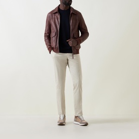 Model wearing Zegna Wool Stripe Sleeve Sweater in navy, styled with brown leather jacket, cream trousers and taupe trainers