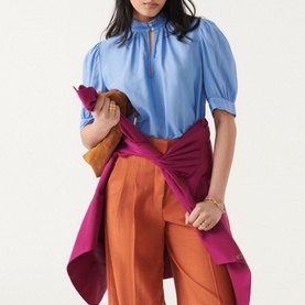 Model wearing Bash Tyler Top in blue with short balloon sleeves, stand-up collar and pintuck pleats