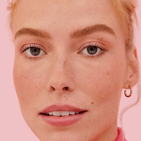 Model with Benefit Goof Proof Brow Powder, showcasing naturally defined brows and fresh skin on a pink background