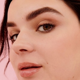Model with Benefit Goof Proof Brow Powder, showcasing defined, filled brows with a natural finish on a pink background